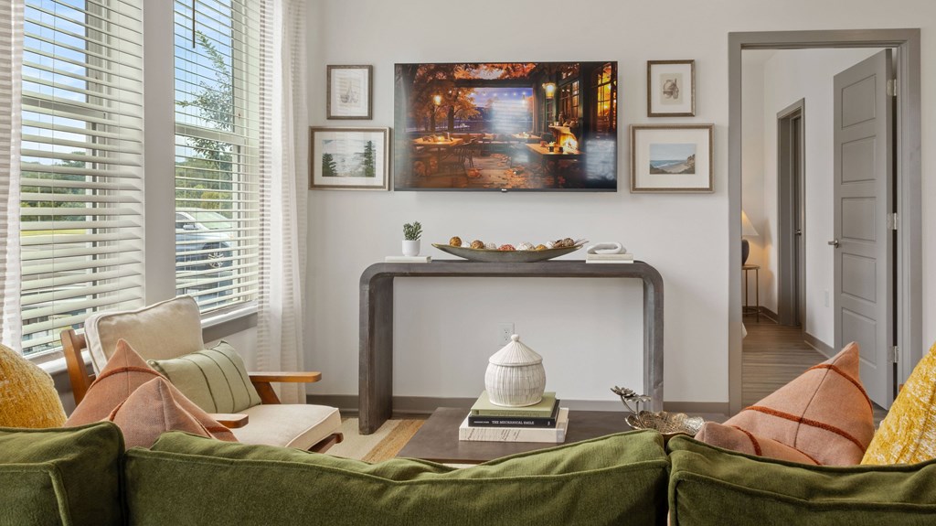 A living room with a green couch and a painting on the wall.
