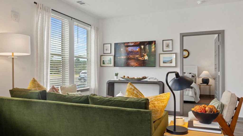A living room with a green couch and a lamp.