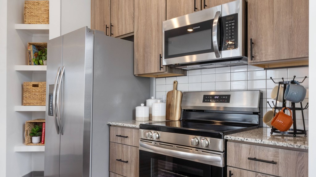 A modern kitchen with a stainless steel refrigerator, microwave, and oven.