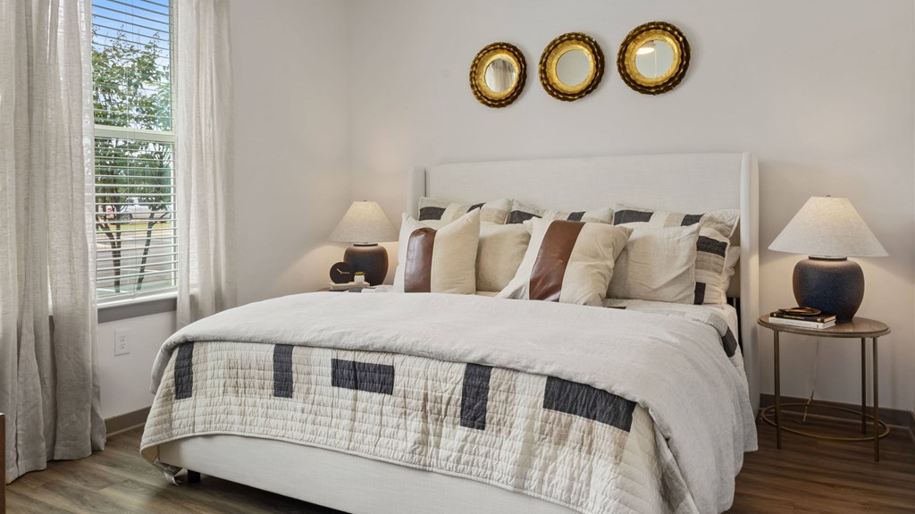 A bedroom with a large bed and a window with curtains.