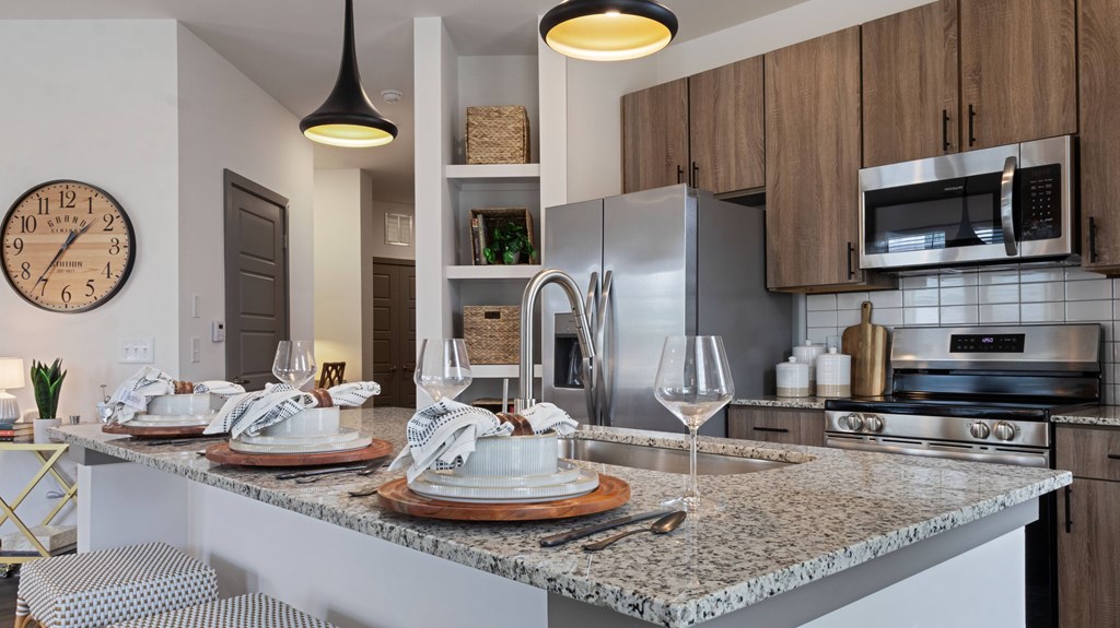 A modern kitchen with a marble countertop and stainless steel appliances.
