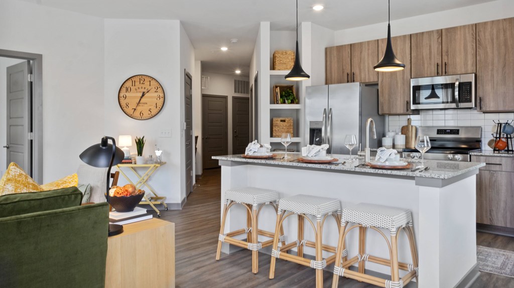 A kitchen with a white counter and bar stools.