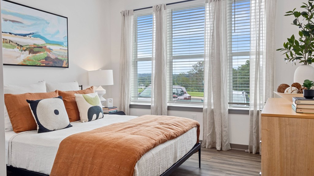 A bedroom with a large bed and a painting on the wall.