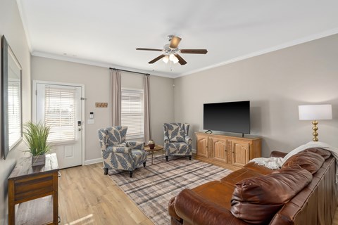 A living room with a brown leather couch and a flat screen TV.