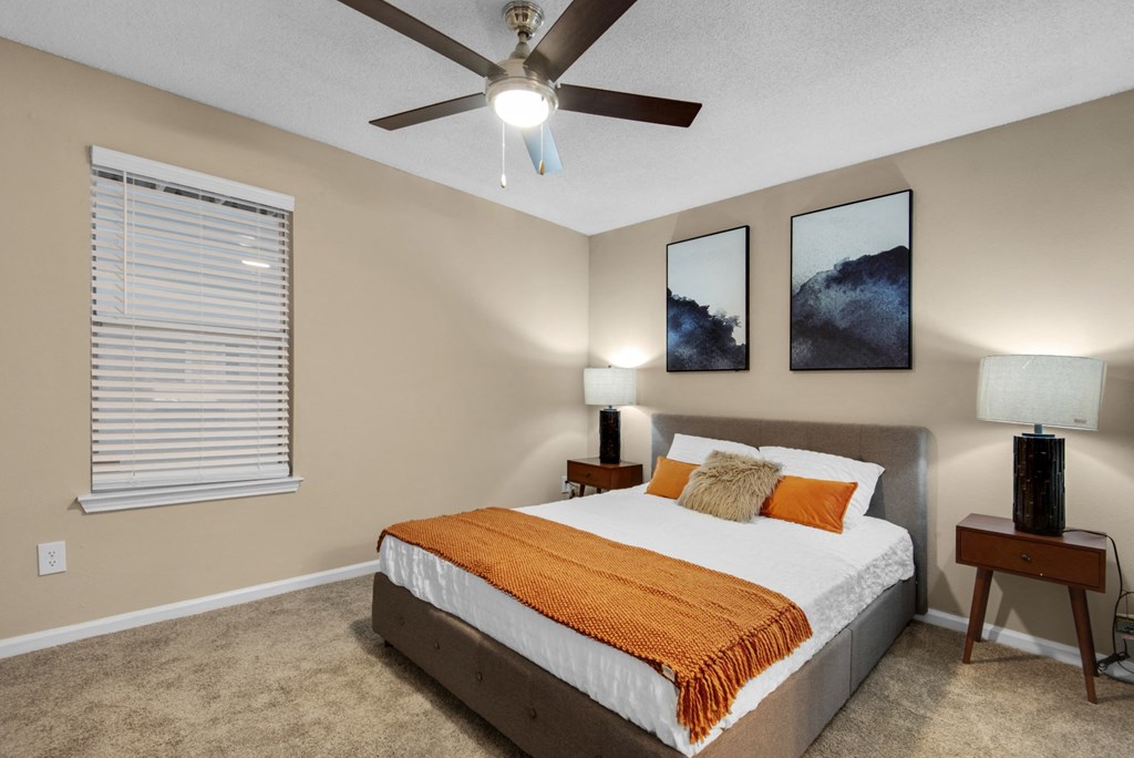 A bedroom with a bed, two nightstands, a window, and a ceiling fan at Crystal Lake in Pensacola, Florida.