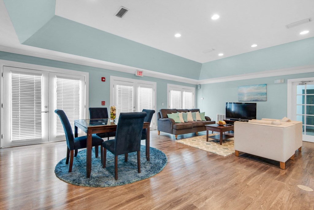 A modern clubhouse with tables and a lounge area with a TV at Crystal Lake in Pensacola, Florida.