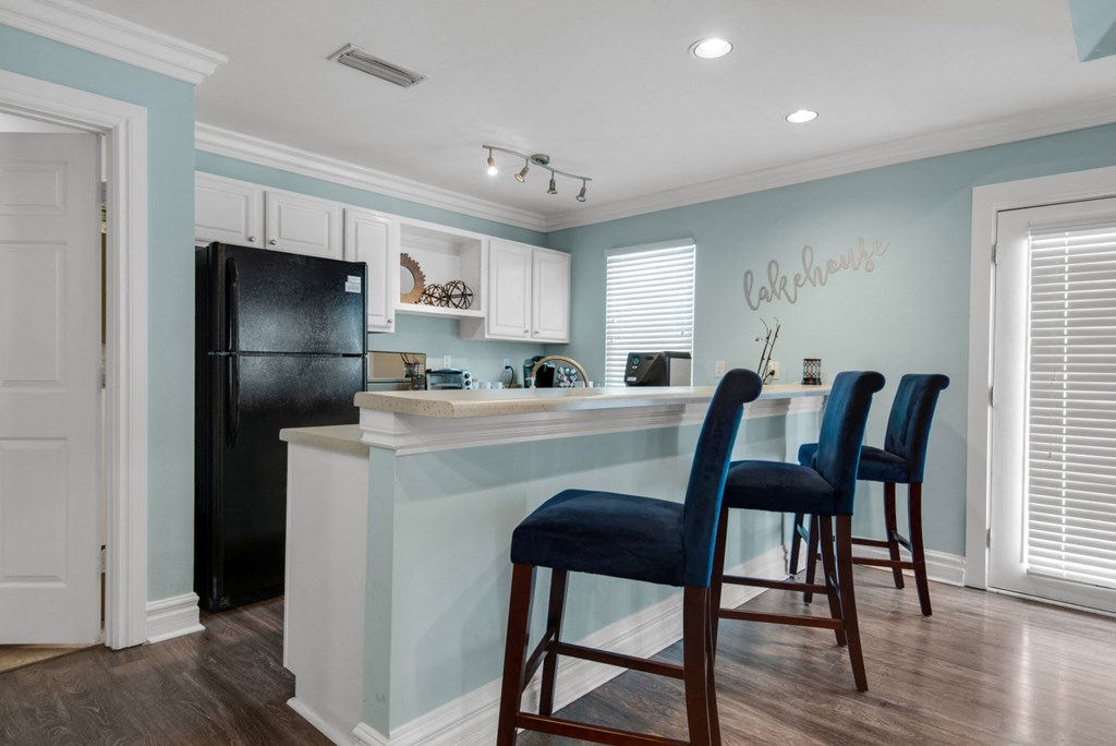 Clubhouse kitchen with a black refrigerator and white cabinets at Crystal Lake in Pensacola, Florida.