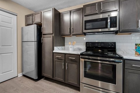 A kitchen with a black stove top oven and a black microwave above it.