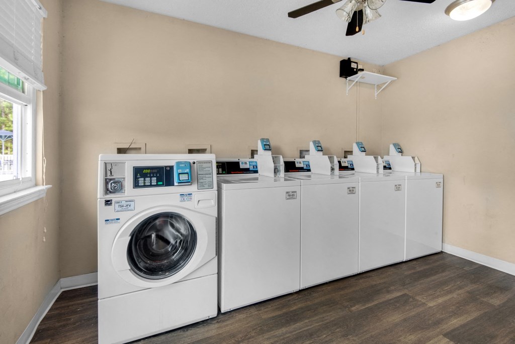 A washing machine and a row of dryers in a laundry room at Crystal Lake in Pensacola, Florida.