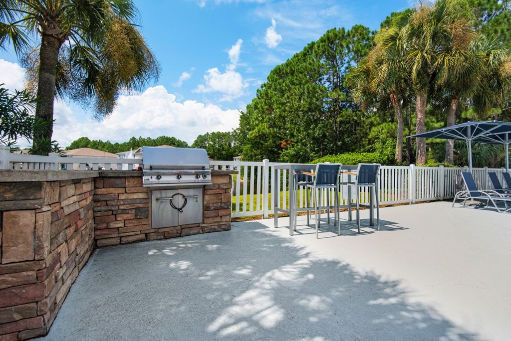 Outdoor grilling station with stone countertops and a seating area at Crystal Lake in Pensacola, Florida.