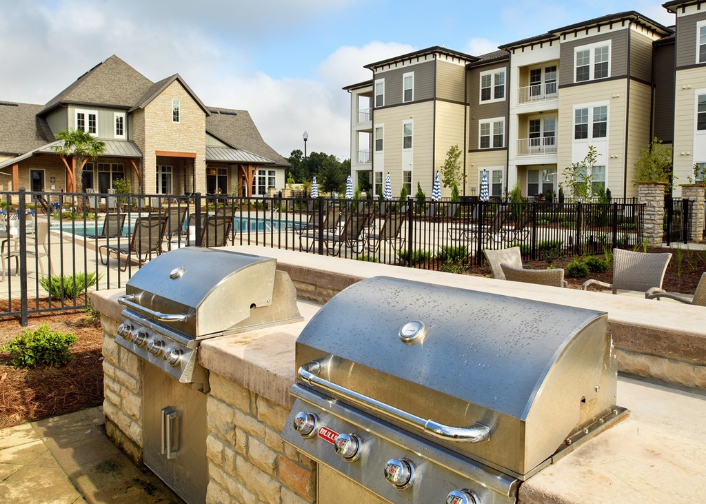 two grills on a stone wall with apartments in the background