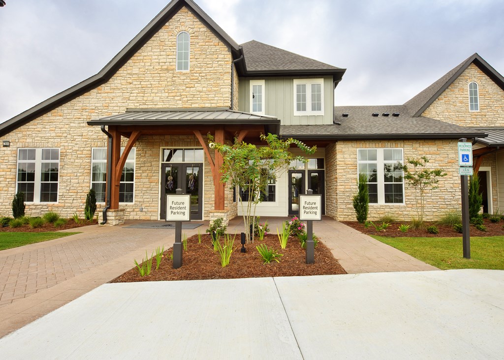 the front of a brick house with a sidewalk and a sign in front of it