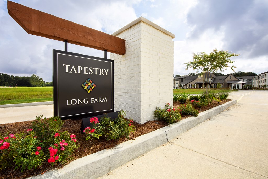 the sign for tapestry long farm in front of a building with flowers