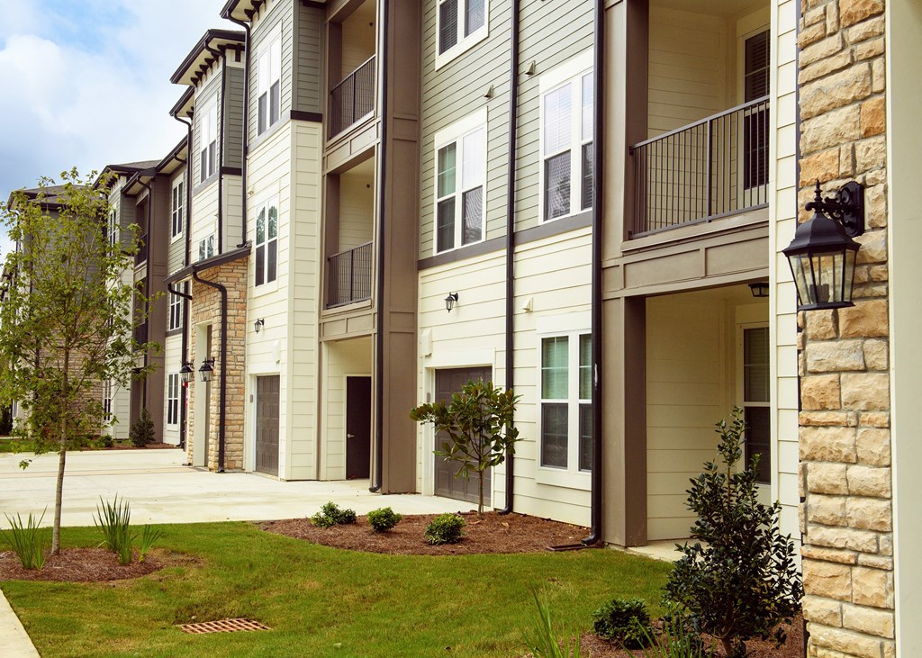 an exterior view of an apartment building with a sidewalk and grass