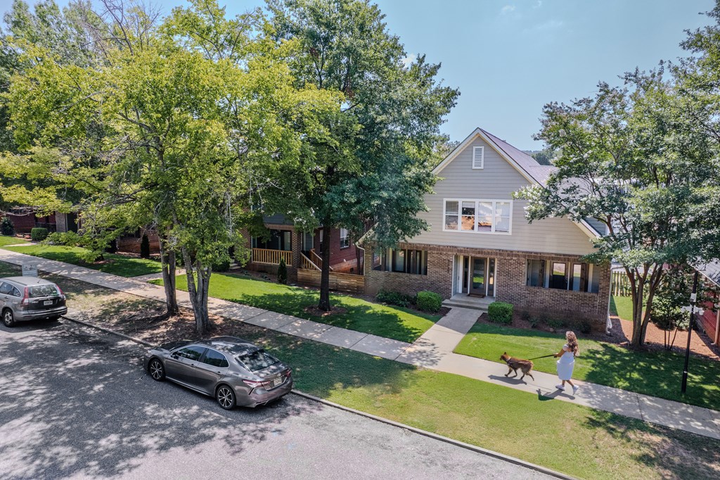 A woman walks her dog in front of a house.