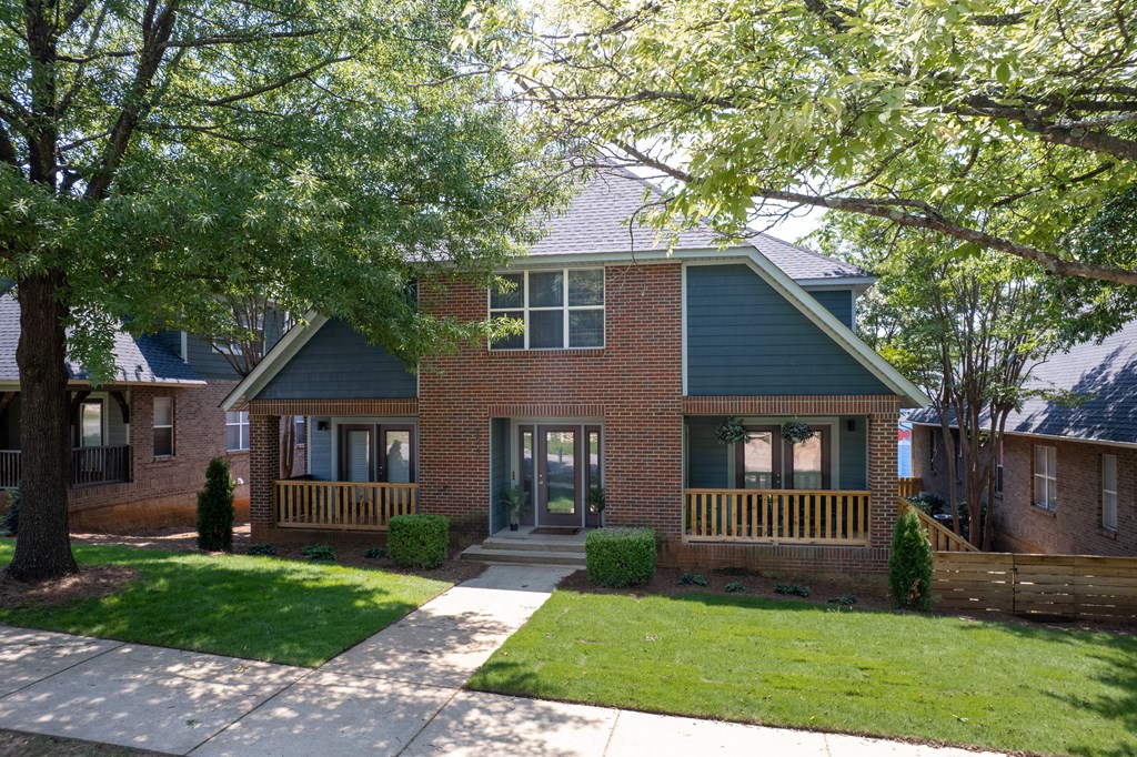 A house with a green lawn and a tree in front.