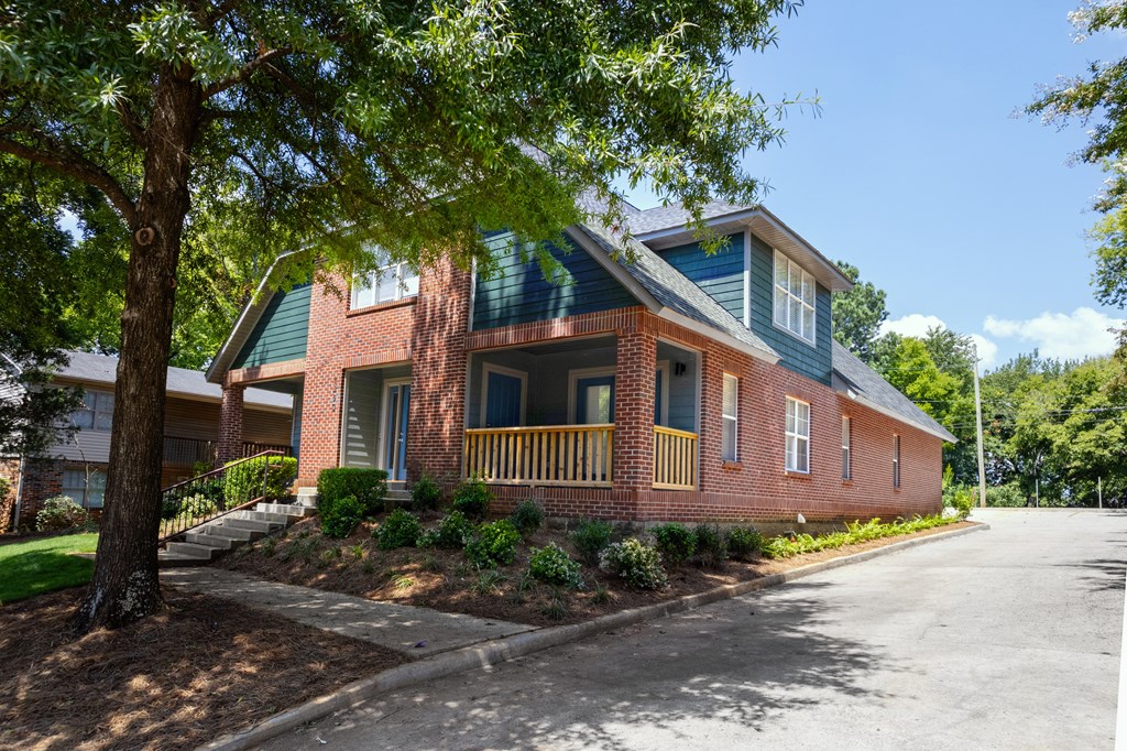 A red brick house with a green roof and a tree in front.