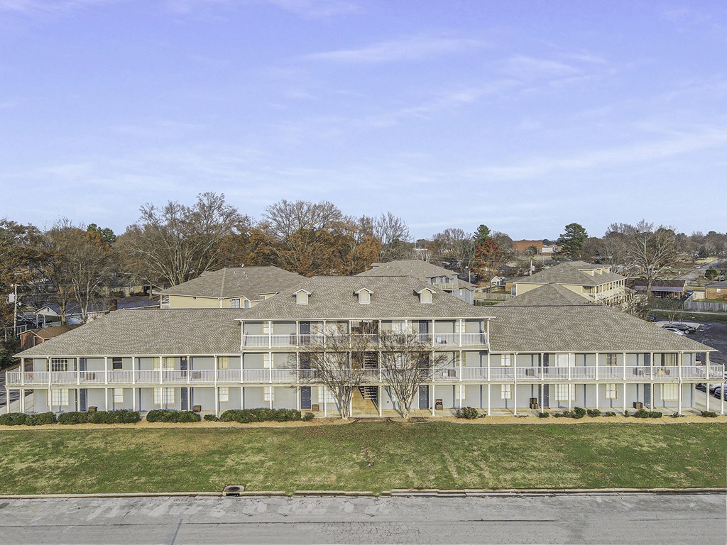 a large white building with a grass field in front of it