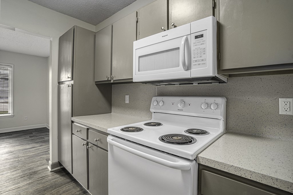 an empty kitchen with white appliances and a microwave over the stove
