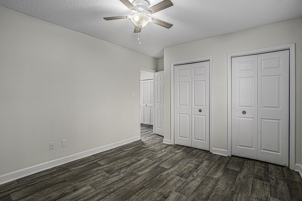 an empty living room with a ceiling fan and white doors
