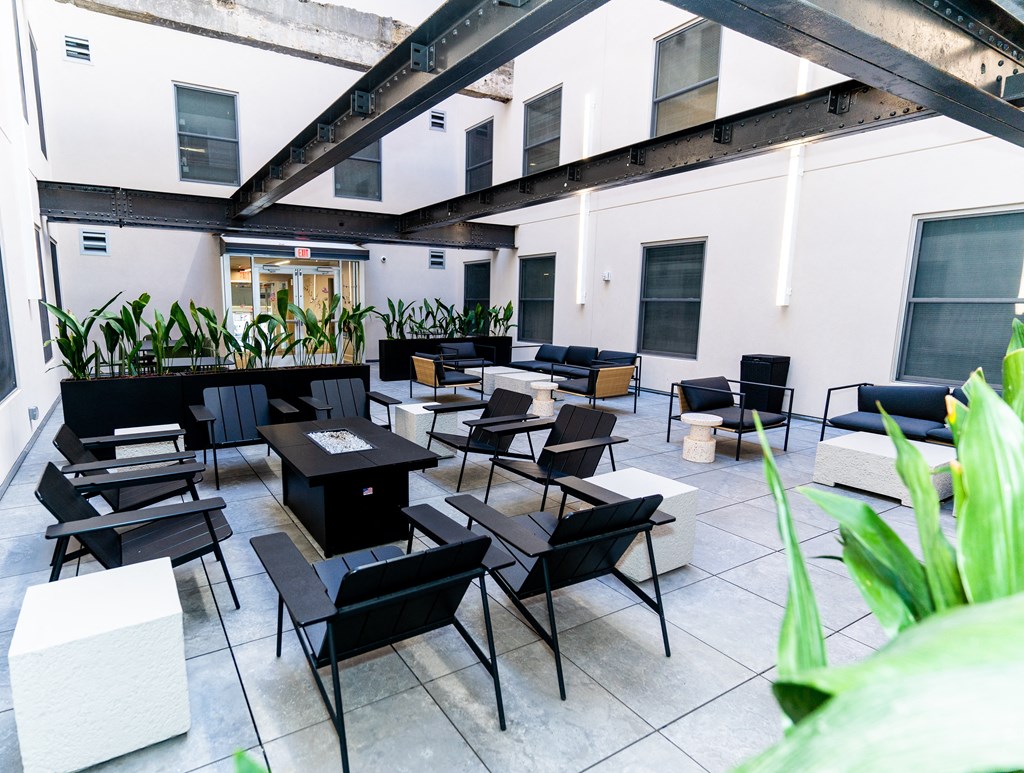 Downtown Birmingham Apartments - Courtyard With A Fire Pit, Chairs, Tables, And Potted Plants.