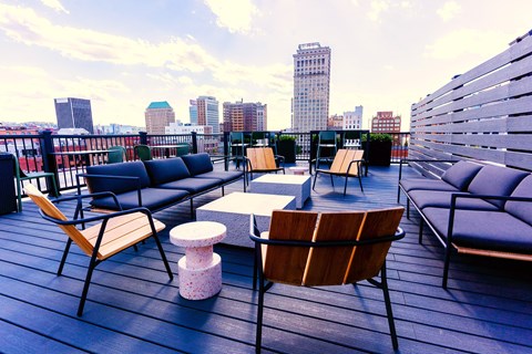 a rooftop deck with couches and chairs and a view of the city