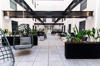 a large lobby with a swing chair and plants