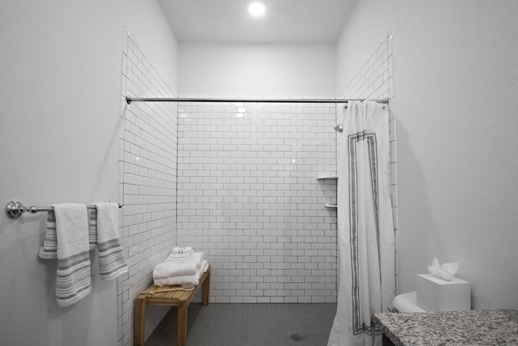 a white bathroom with a shower and a table with towels at 20 Midtown, Birmingham, Alabama