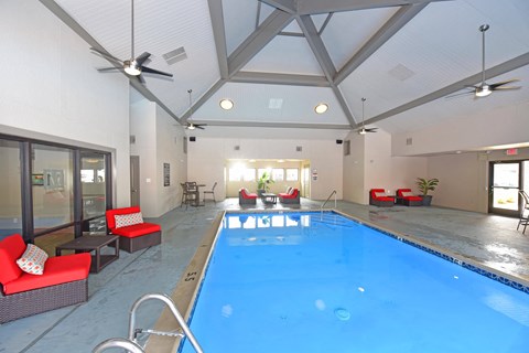 a large indoor pool with red chairs and a blue water