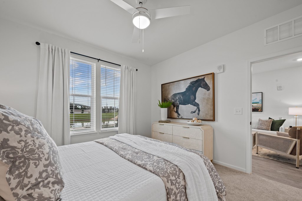 A bedroom with a large bed and a painting of a horse on the wall.