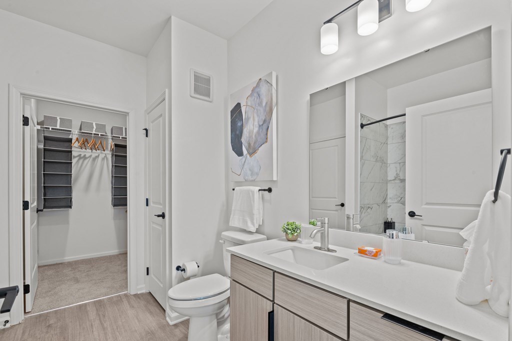 A white bathroom with a toilet, sink, and mirror.