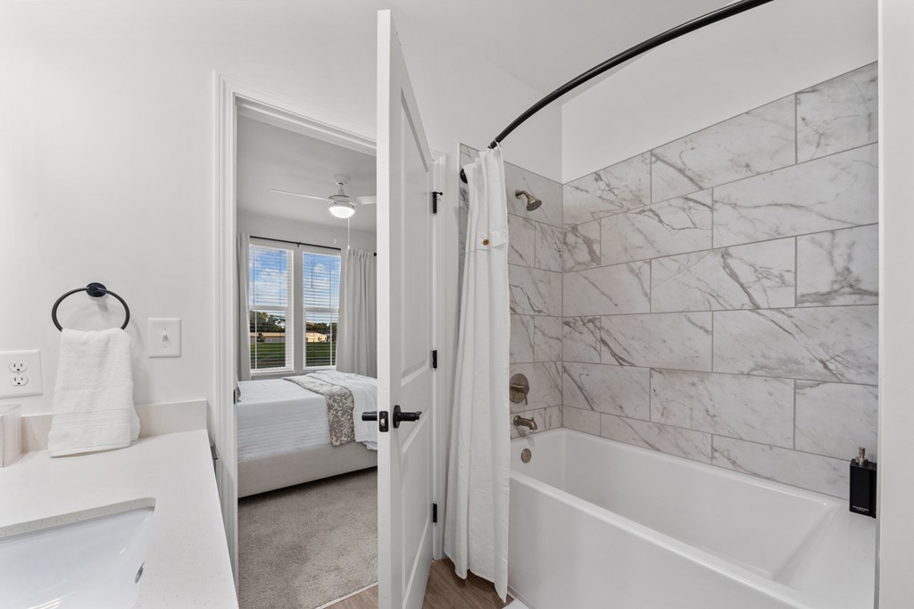 A white bathroom with a marble wall and a white bathtub.