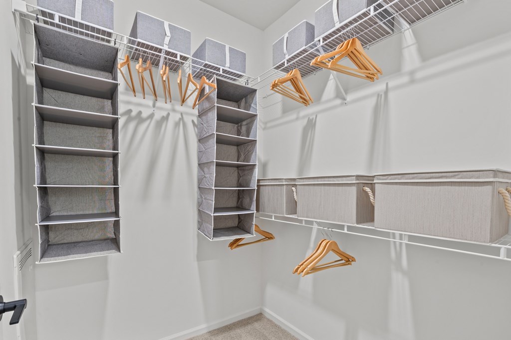 A white closet with clothes hanging on hangers.