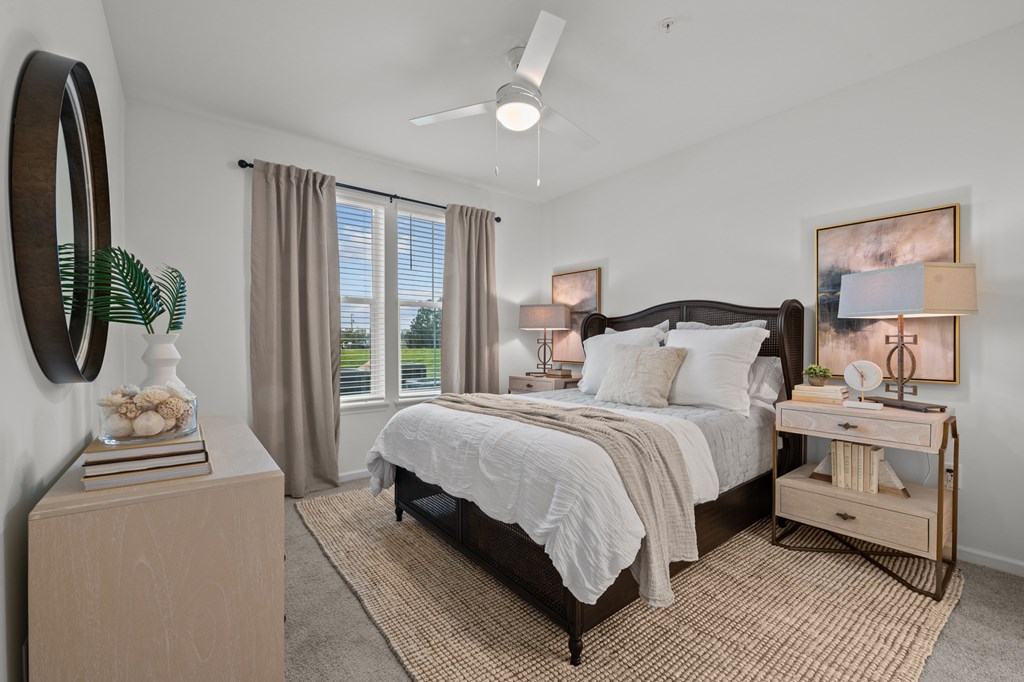 A bedroom with a large bed, a nightstand, and a window with curtains.