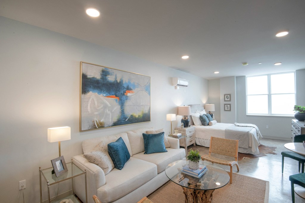 a living room with a couch and a chair and a bedroom with beds