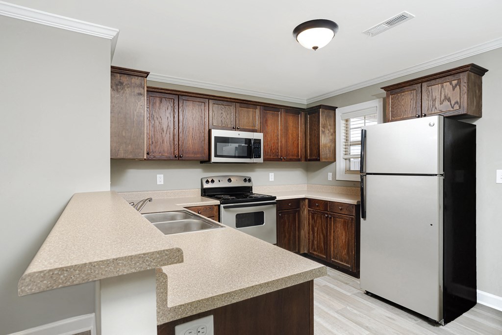 a kitchen with stainless steel appliances and wooden cabinets at Deerfield Apartments in Florence, AL