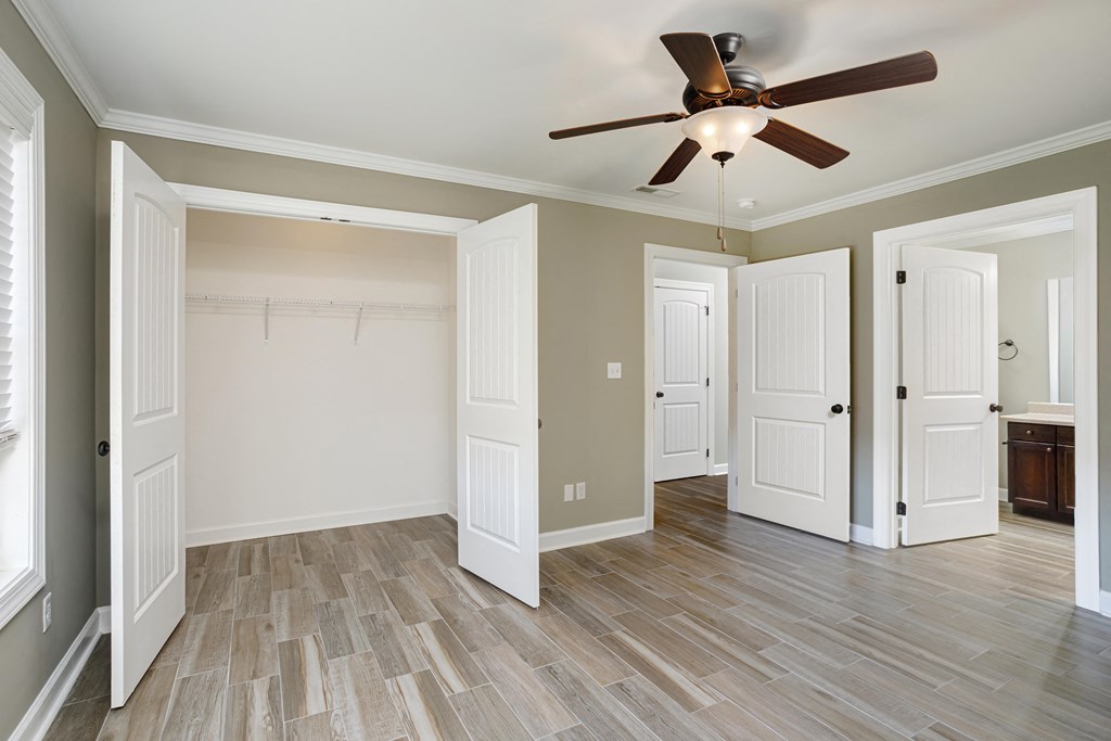 a bedroom with ensuite bathroom and ceiling fan and wood floors at Deerfield Apartments in Florence, AL