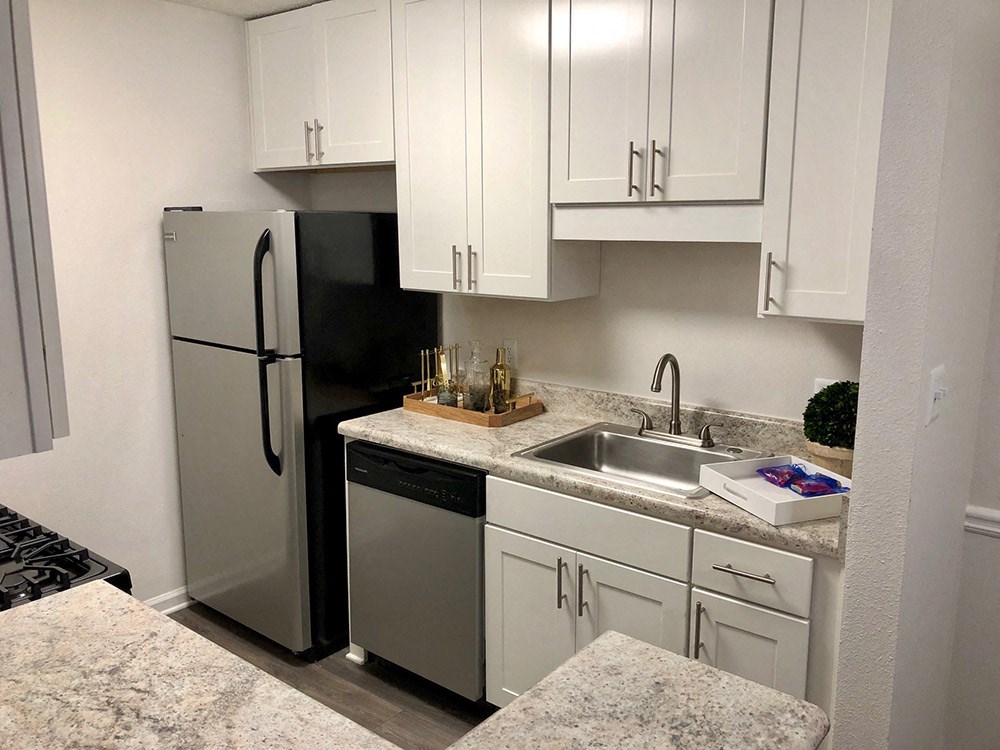 a kitchen with white cabinets and a stainless steel refrigerator