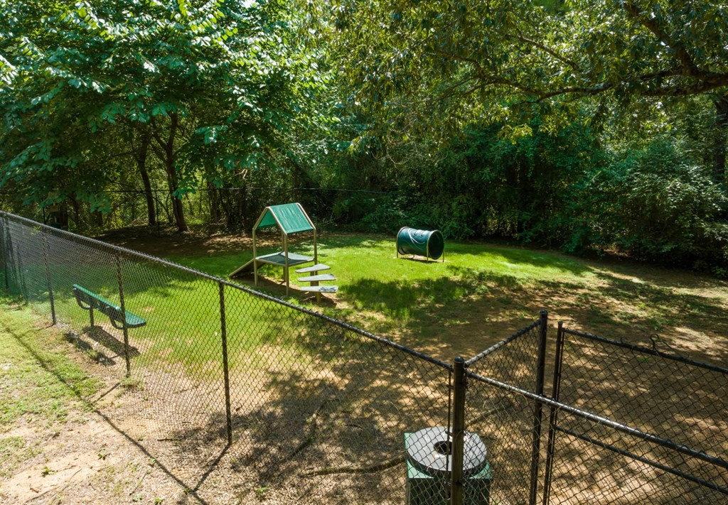 The pet bark park with trees and obstacles and a bench at Summerchase at Riverchase in Hoover, Alabama.