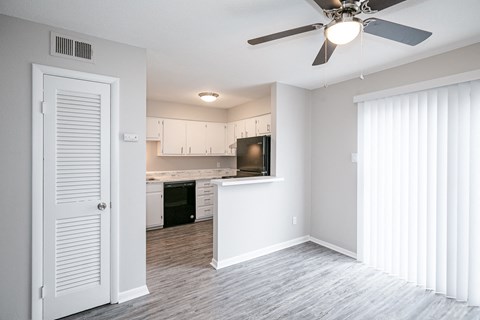 an empty living room and kitchen with a ceiling fan