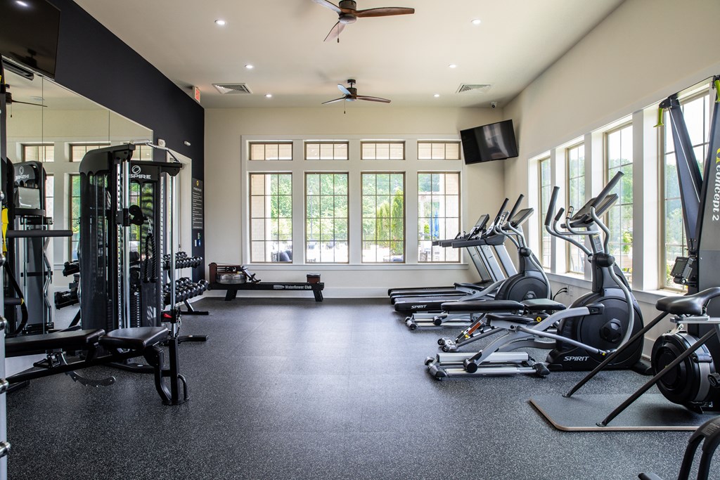 a gym with weights and cardio equipment and windows