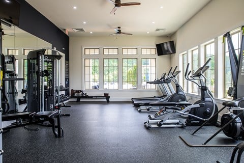 a gym with weights and cardio equipment and windows