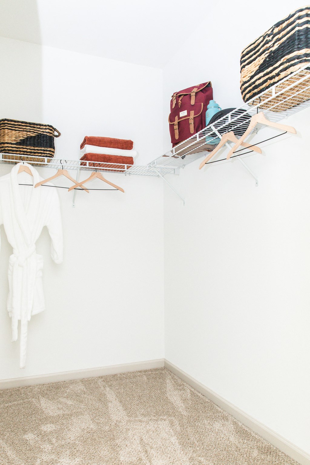 a room with white walls and a white closet with clothes and luggage on a rack