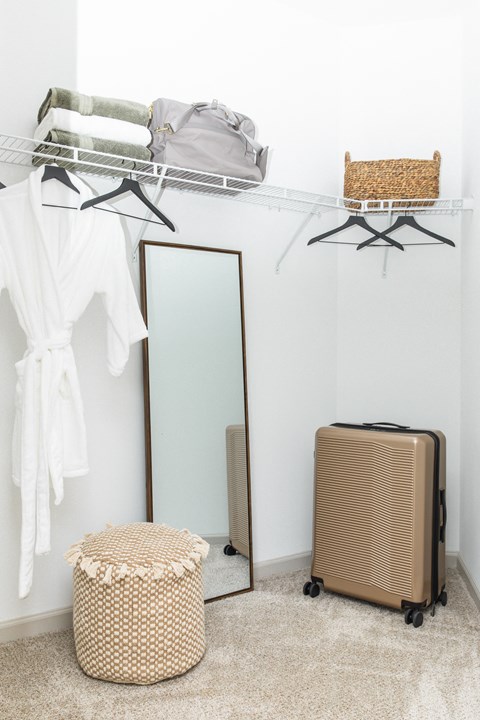 a closet with a mirror and a wardrobe with clothes and a basket