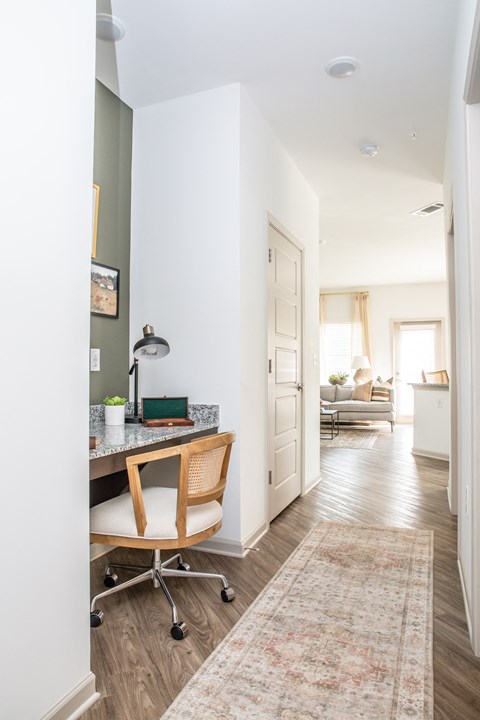 a home office with a desk and a hallway to a living room