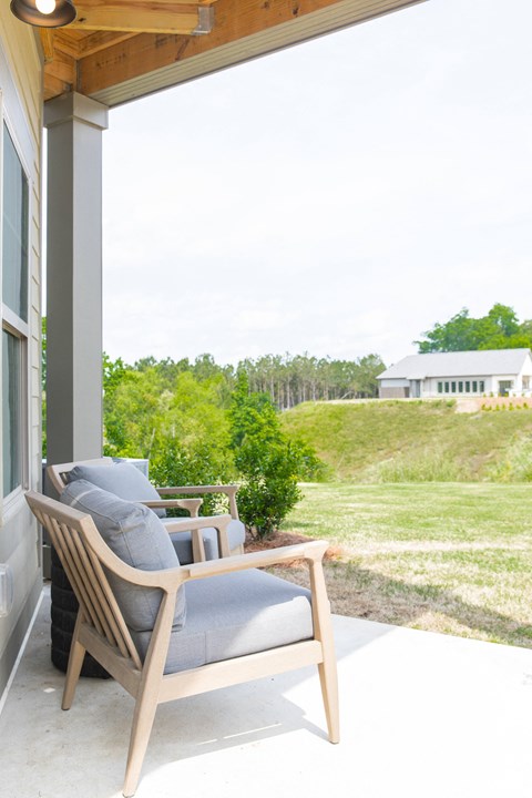 the porch of a home with a chair and a table on it