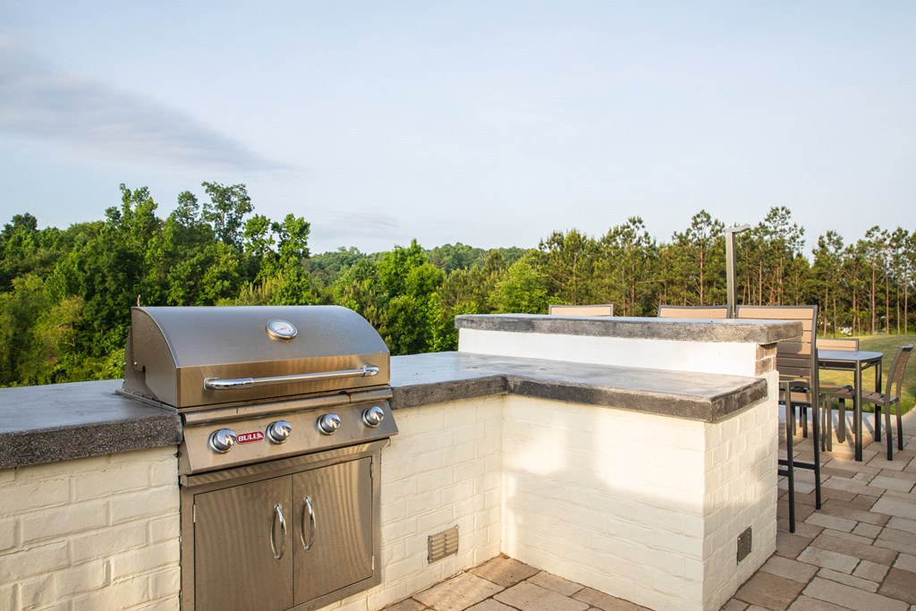 a barbecue grill on a patio with a table and chairs