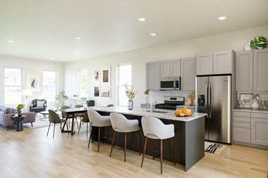 a kitchen with gray cabinets and a large island with white chairs
