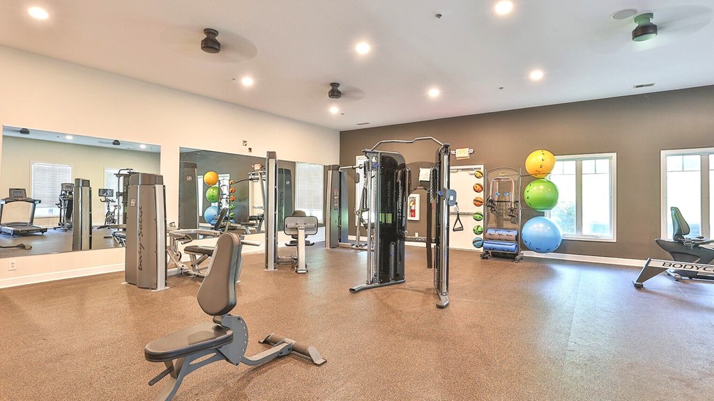 a gym with cardio equipment and weights in a building with windows
