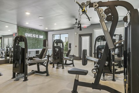 a gym with weights and cardio equipment and a sign on the wall